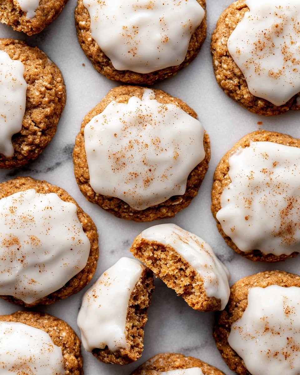 A close-up top view shows a group of round cookies arranged on a white marbled surface. Each cookie has a rough, crunchy-looking brown base with a thick layer of smooth white icing spread unevenly on top. The icing has a slightly glossy texture and is sprinkled lightly with a fine dusting of brown spice, giving a warm contrast. One cookie near the center is broken in half, exposing its dense, crumbly interior beneath the icing. The cookies are touching each other, creating a cozy, homemade feel. photo taken with an iphone --ar 4:5 --v 7