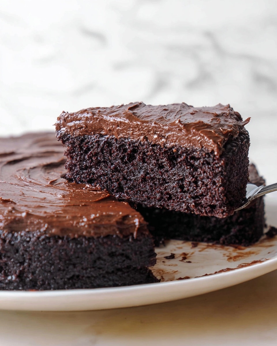 A rich, dense chocolate cake with two layers is shown on a white plate. The bottom layer is a thick, dark chocolate cake with a moist and slightly crumbly texture. The top layer is a glossy, thick chocolate frosting with a slightly uneven, textured surface that spreads generously over the cake. A slice is being lifted by a spatula, showing the dense cake inside and the thick chocolate top layer. The background features a white marbled texture. photo taken with an iphone --ar 4:5 --v 7