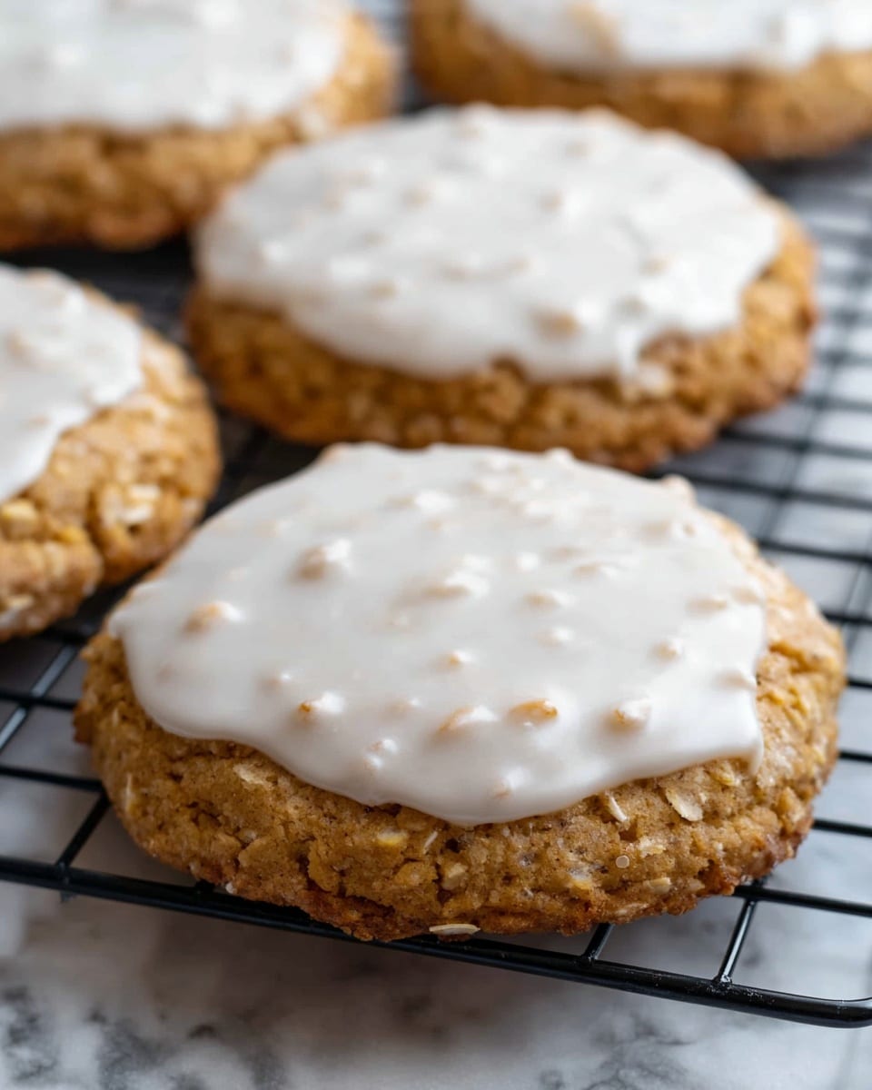 The image shows a close-up of five round cookies with a rough, slightly bumpy texture. Each cookie has two layers: a golden brown, thick base with a grainy surface and a thin white icing layer on top that looks smooth but uneven with small bumps, partially covering the brown base. The cookies rest on a black metal cooling rack, which is placed on a white marbled surface. The lighting highlights the uneven texture of the icing and the graininess of the cookie base. photo taken with an iphone --ar 4:5 --v 7