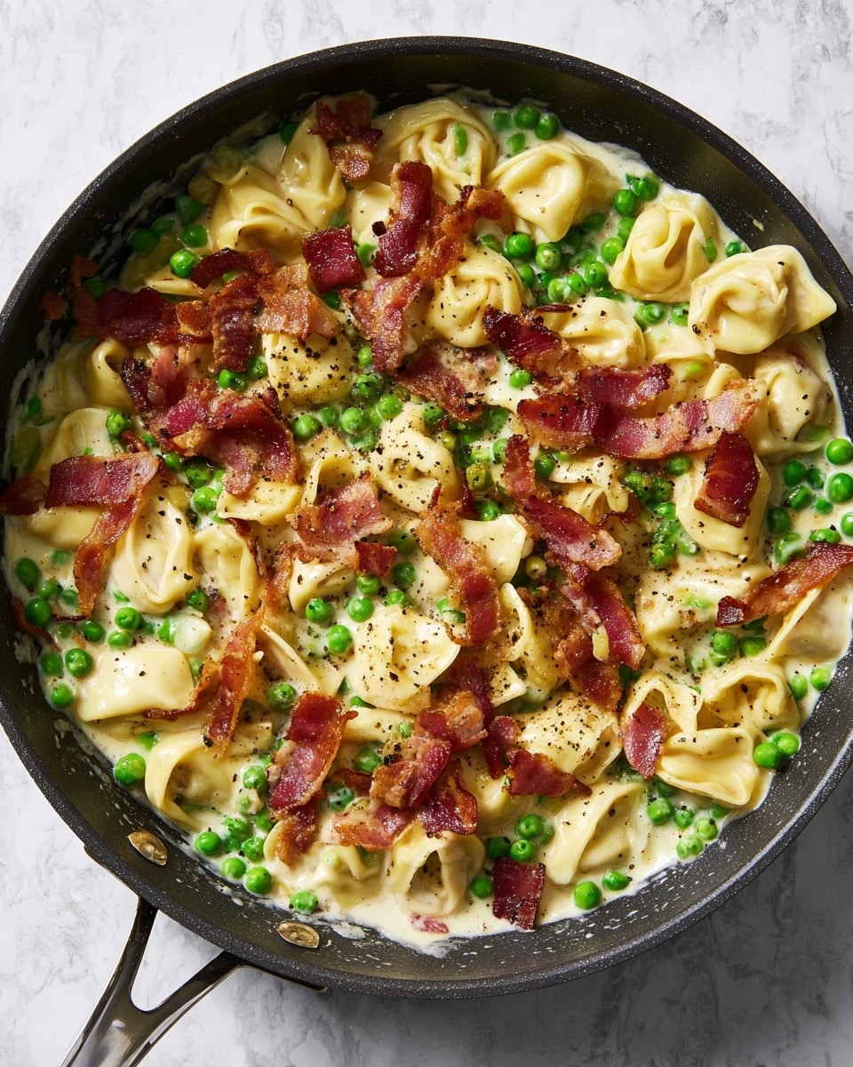 The dish is a close-up view of a black cast iron pan filled with creamy tortellini pasta, bright green peas scattered throughout, and fresh cut asparagus pieces mixed in. On top, there are small crispy reddish-brown bacon bits and a light sprinkle of finely grated cheese, all seasoned with black pepper. The tortellini pieces are golden-yellow with a soft texture, creating a colorful and inviting mix with the vibrant green vegetables and bacon. The pan sits on a surface with a white marbled texture. Photo taken with an iphone --ar 4:5 --v 7