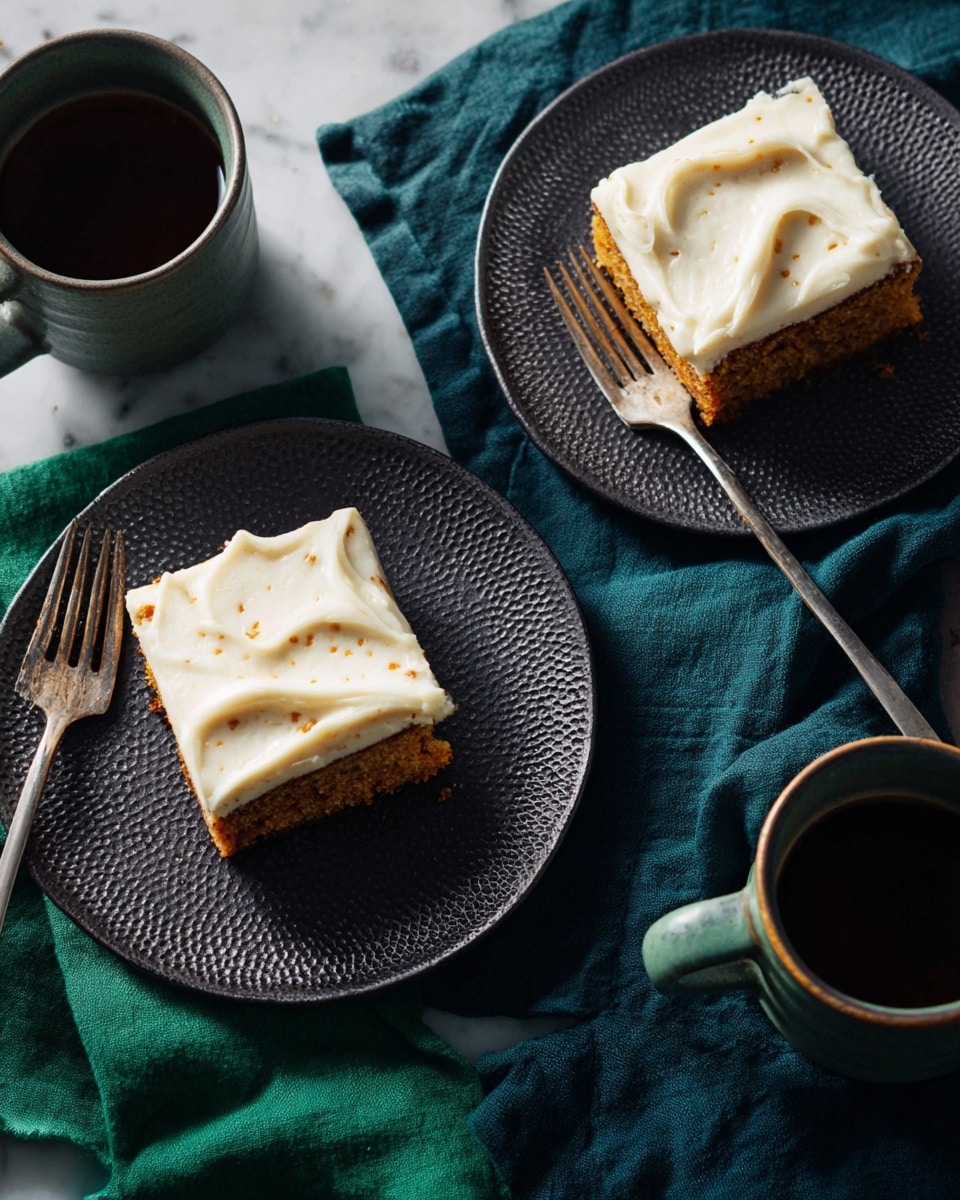 Two square pieces of carrot cake with creamy white frosting on top are placed on two textured dark plates, each with a fork resting beside the cake. The cakes have a golden-brown spongy base with a thick layer of smooth, slightly swirled frosting that has visible small brown specks. The scene is set on a white marbled texture with dark green and blue cloth napkins under the plates. Two ceramic mugs filled with a dark brown beverage are also visible in the frame. photo taken with an iphone --ar 4:5 --v 7