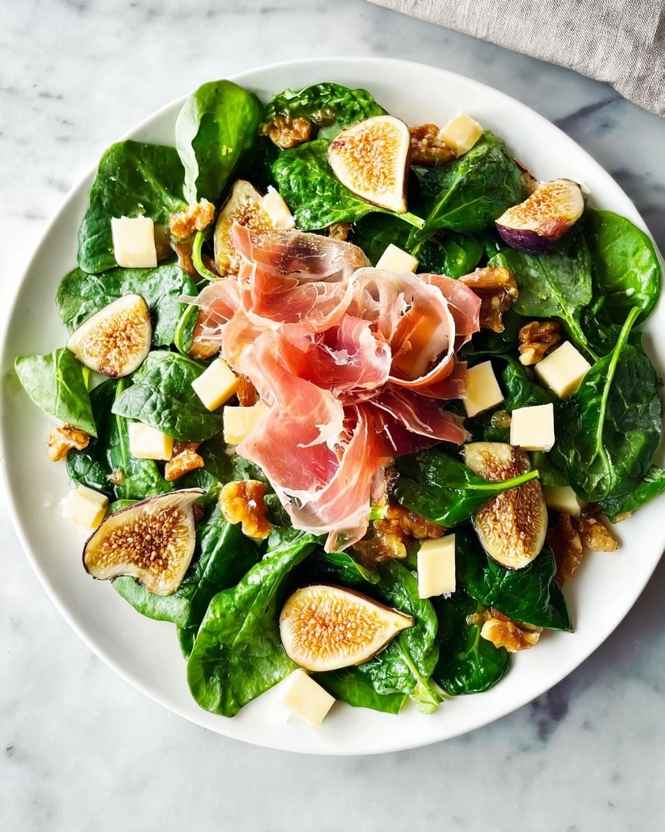 A white plate filled with fresh dark green spinach leaves forms the base layer, scattered evenly across the plate. On top, there are small cubes of pale yellow cheese spread throughout, along with golden-brown candied walnuts adding texture and color contrast. In the center, delicate pink slices of prosciutto are loosely folded, creating a soft, ruffled focal point. Thin slices of dried figs with speckled brown and beige tones are placed intermittently over the spinach. The plate is set on a white marbled surface. photo taken with an iphone --ar 4:5 --v 7
