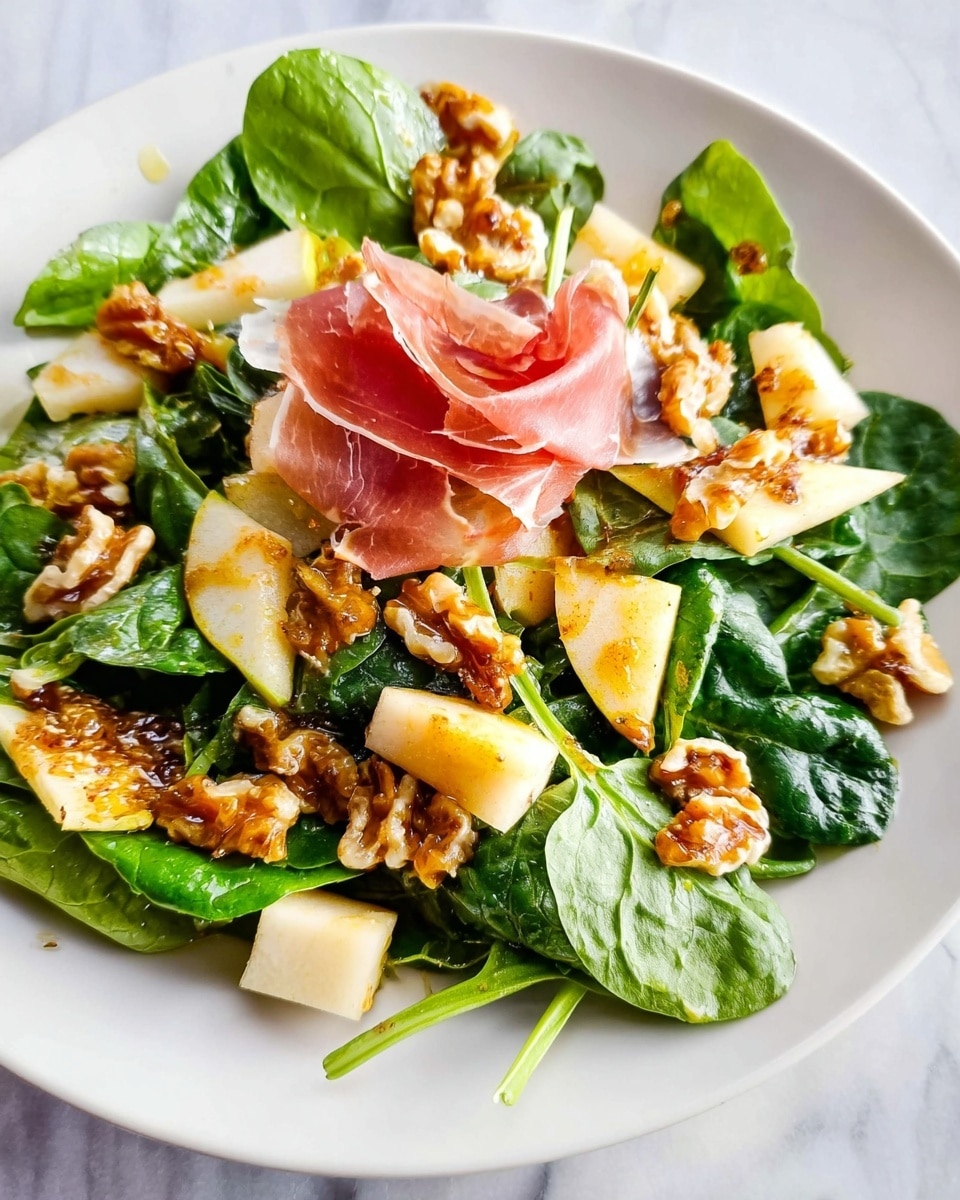 A fresh salad on a white round plate rests on a white marbled surface, showing layers of dark green spinach leaves as the base, topped with light beige cubed pieces of pear scattered evenly. On top, there are golden-brown candied walnuts with a glossy texture and some dried figs with a speckled appearance. A thin, pink slice of prosciutto is delicately folded in the center, adding a soft, smooth layer above the greens. The salad appears lightly dressed, giving the spinach a slight shine. photo taken with an iphone --ar 4:5 --v 7
