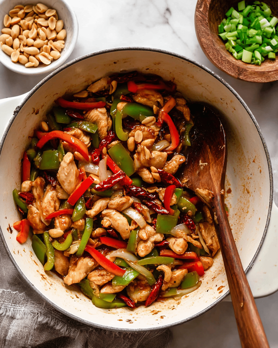 A white plate holds a serving of steamed white rice as the bottom layer, topped with a colorful stir-fry mix of sliced red and green bell peppers, beige chicken pieces, thin onion strips, and whole peanuts coated with a shiny, slightly thick brown sauce, garnished with chopped green onions and a few dried red chilies for contrast. Two light brown wooden chopsticks rest on the rice edge, crossing each other. The plate is set on a white marbled surface with small green herb leaves scattered around. photo taken with an iphone --ar 4:5 --v 7