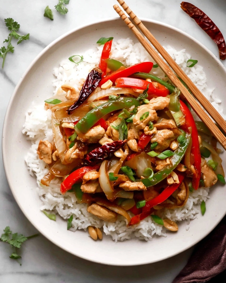 A white pot filled with a colorful stir-fry featuring several layers: the bottom and main layer consists of light brown cooked chicken pieces mixed with bright red and green sliced bell peppers and thin cuts of translucent white onion, all coated in a glossy sauce. Scattered throughout are whole roasted light brown peanuts and small bits of thin dark red dried chili peppers. A wooden spoon rests inside the pot on the right side, slightly stained with sauce. In the background, a small white bowl of peanuts sits on a white marbled surface near a wooden bowl filled with chopped green onions. Photo taken with an iphone --ar 4:5 --v 7