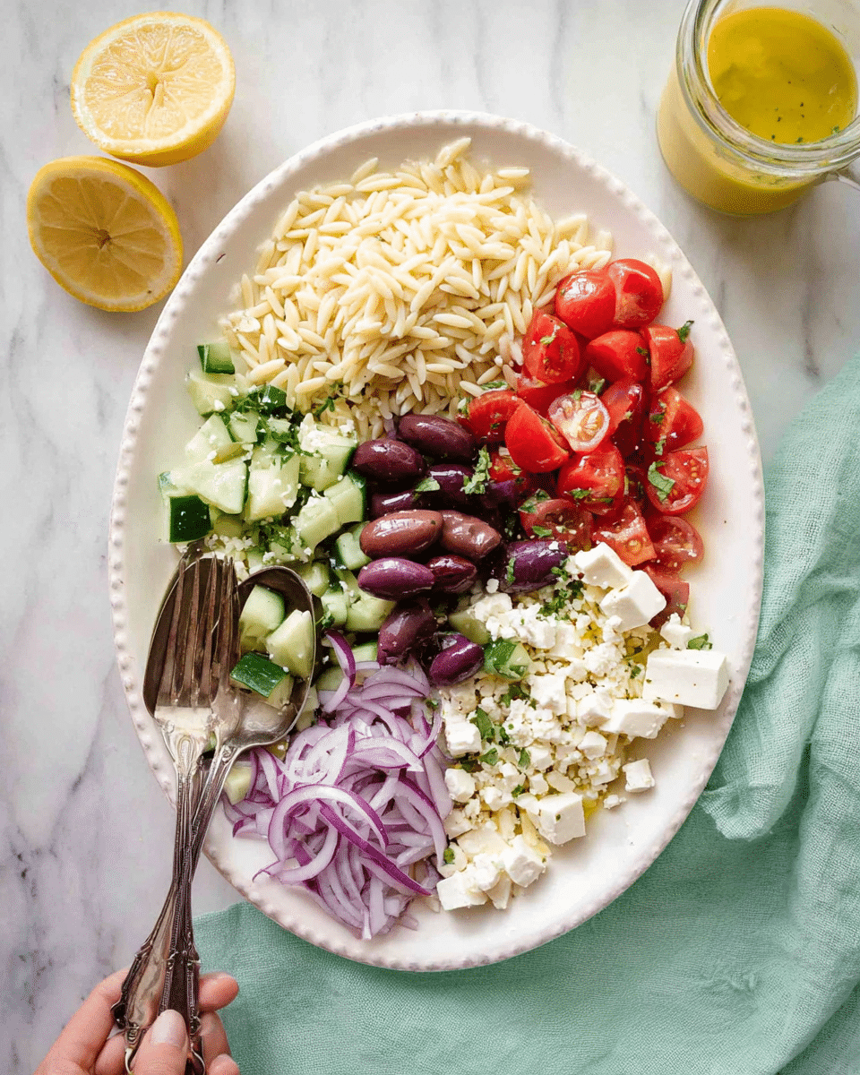 A large white oval plate shows a fresh salad with five distinct sections. At the top left is a light beige layer of cooked orzo pasta. Next to this on the right is a bright red layer of halved cherry tomatoes mixed with small white cubes of feta cheese. On the bottom right is a bigger group of white feta cheese cubes. Below the orzo and to the left of the feta is a fresh green layer of chopped cucumbers mixed with some halved dark purple olives and thin slices of purple-red onion scattered all around. A woman's hand is holding a fork and spoon placed on the plate’s left edge. In the background is a white marbled surface with half a lemon and a small glass jar of yellow dressing. A light green cloth partially surrounds the plate. photo taken with an iphone --ar 4:5 --v 7