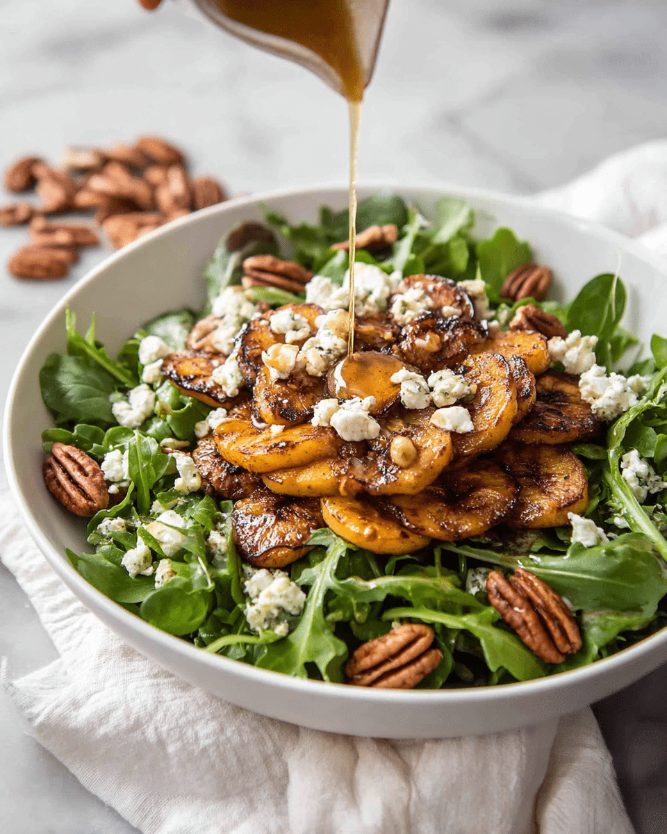 A white bowl is filled with a base layer of fresh, bright green leafy arugula. On top of the greens, there is a thick layer of golden-brown roasted or grilled plantains that have a caramelized and slightly charred texture, arranged in the center. Scattered around the plantains and greens are medium-sized, glossy brown pecan halves. Crumbled white cheese is sprinkled generously over the entire dish, adding a crumbly texture and light contrast. A golden-colored sauce or dressing is being poured over the top from above, creating a thin stream that falls directly onto the plantains, adding a shiny, wet finish in spots. The bowl sits on a white marbled surface with a white cloth and some loose pecans nearby. A woman's hand is holding the container pouring the sauce. Photo taken with an iphone --ar 4:5 --v 7