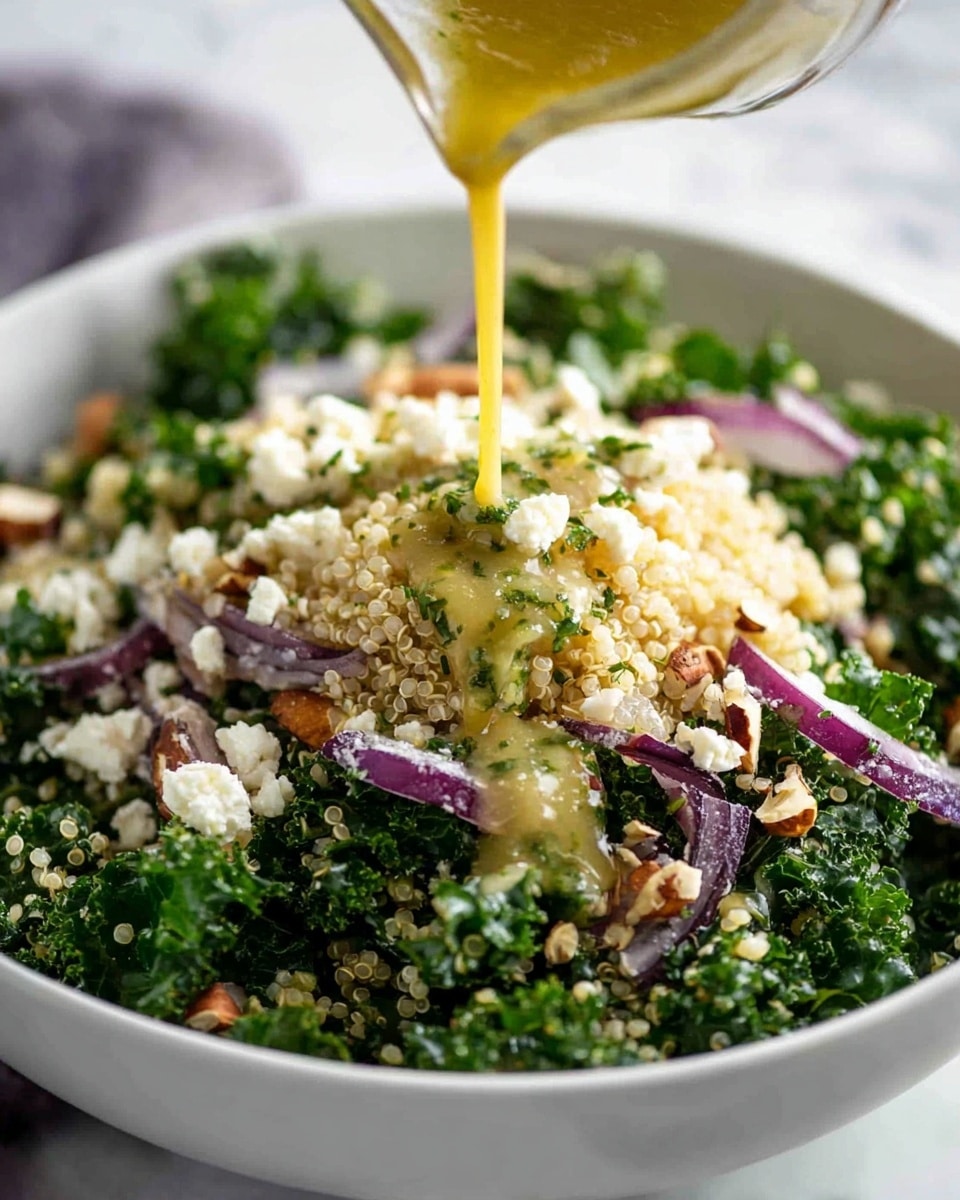 A close-up of a white bowl filled with a fresh, textured salad that has about three visible layers. The bottom layer is made of bright green kale leaves, curly and finely chopped. The middle layer consists of light beige quinoa grains, soft and fluffy. Scattered on top and mixed throughout are thin slices of purple onion, small white crumbles resembling cheese, and chopped light brown nuts adding crunch. A light yellow dressing is being poured from a clear bottle onto the center of the salad, with some herbs visible in the dressing. The bowl sits on a white marbled surface. photo taken with an iphone --ar 4:5 --v 7