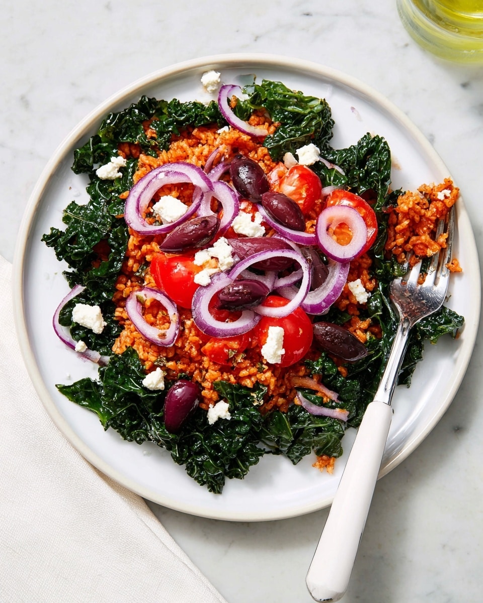 A white plate filled with a colorful dish featuring two main layers: the bottom layer is dark green leafy kale with a slightly glossy texture, spread around the plate, and the top layer is reddish-orange seasoned rice piled in the center. On top of the rice and kale are scattered slices of purple-red Kalamata olives, bright red halved cherry tomatoes, thin curved slices of light purple onion, and small white crumbles of feta cheese. The mix creates a vibrant contrast of colors and textures with the greens, reds, purples, and whites. A white-handled fork with some olives near its base rests on the edge of the plate, all set against a white marbled textured surface. photo taken with an iphone --ar 4:5 --v 7